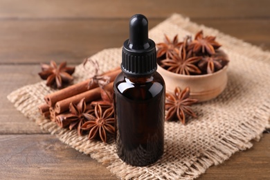 Anise essential oil and spices on wooden table