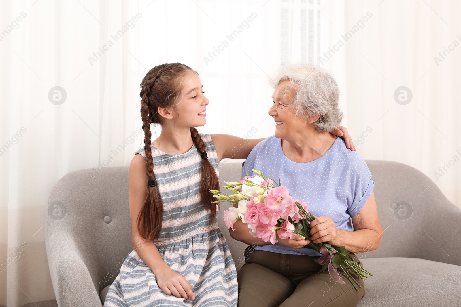 Photo of Happy girl congratulating her grandmother at home