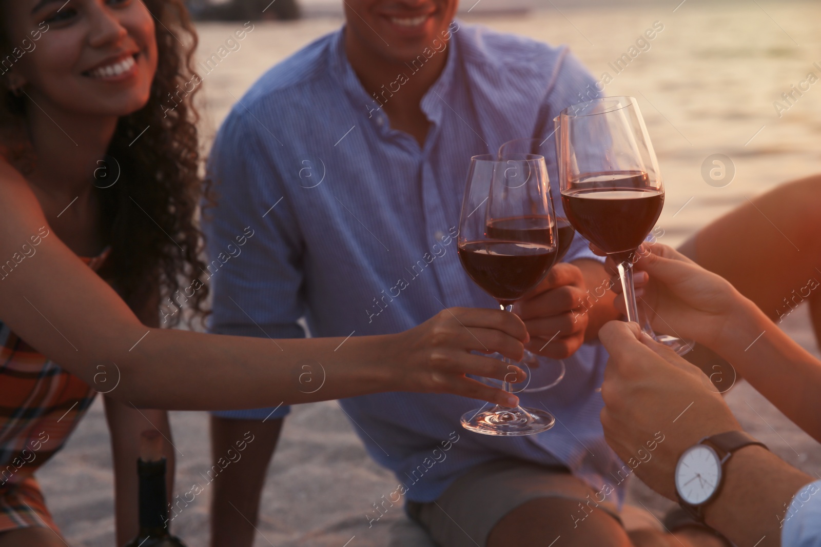 Photo of Group of friends having picnic near river at sunset, closeup