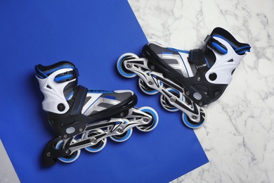 Photo of Pair of inline roller skates on color background, top view
