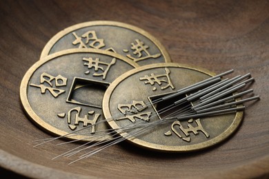 Acupuncture needles and Chinese coins in wooden bowl, closeup