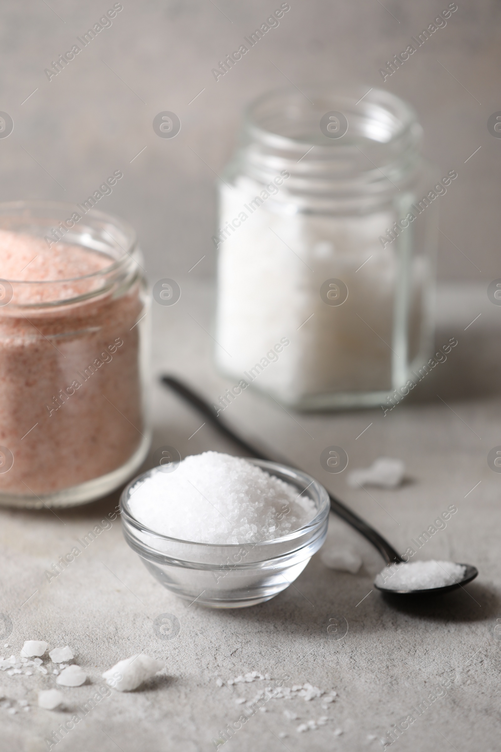 Photo of Different natural salt on grey table, closeup