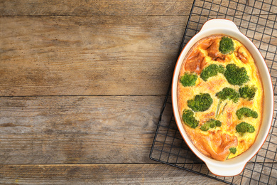 Photo of Tasty broccoli casserole in baking dish on cooling rack, top view. Space for text