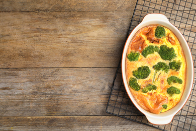 Tasty broccoli casserole in baking dish on cooling rack, top view. Space for text