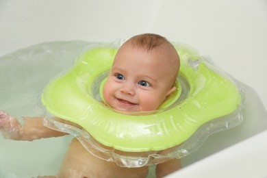 Cute little baby swimming with inflatable ring in bath