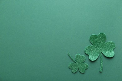 St. Patrick's day. Decorative clover leaves on green background, flat lay. Space for text
