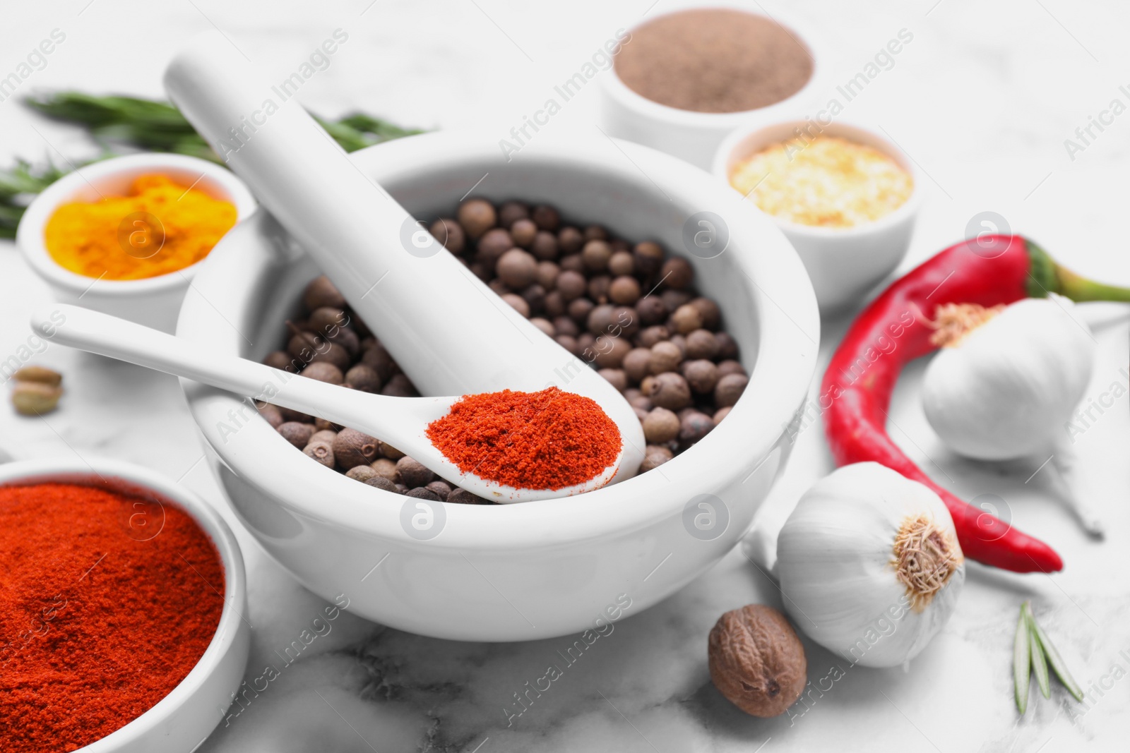 Photo of Mortar and spices on white marble table, closeup