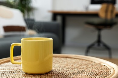 Ceramic mug with hot drink on wicker table indoors. Mockup for design