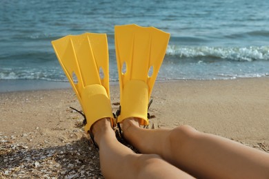 Woman in flippers near sea on beach, closeup