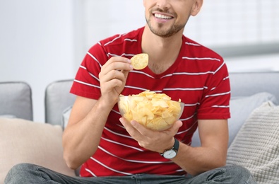 Photo of Man with bowl of potato chips sitting on sofa, closeup