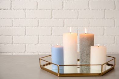 Photo of Tray with decorative candles on table against brick wall