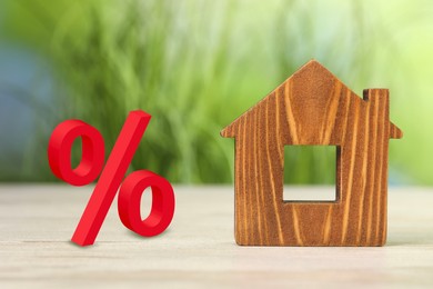 Image of Mortgage rate. Wooden model of house and percent sign on table