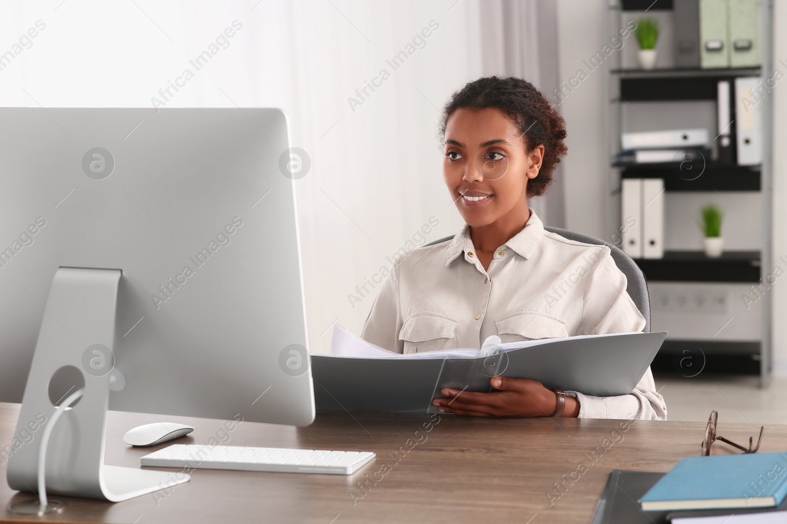 Photo of African American intern with folder working at table in office