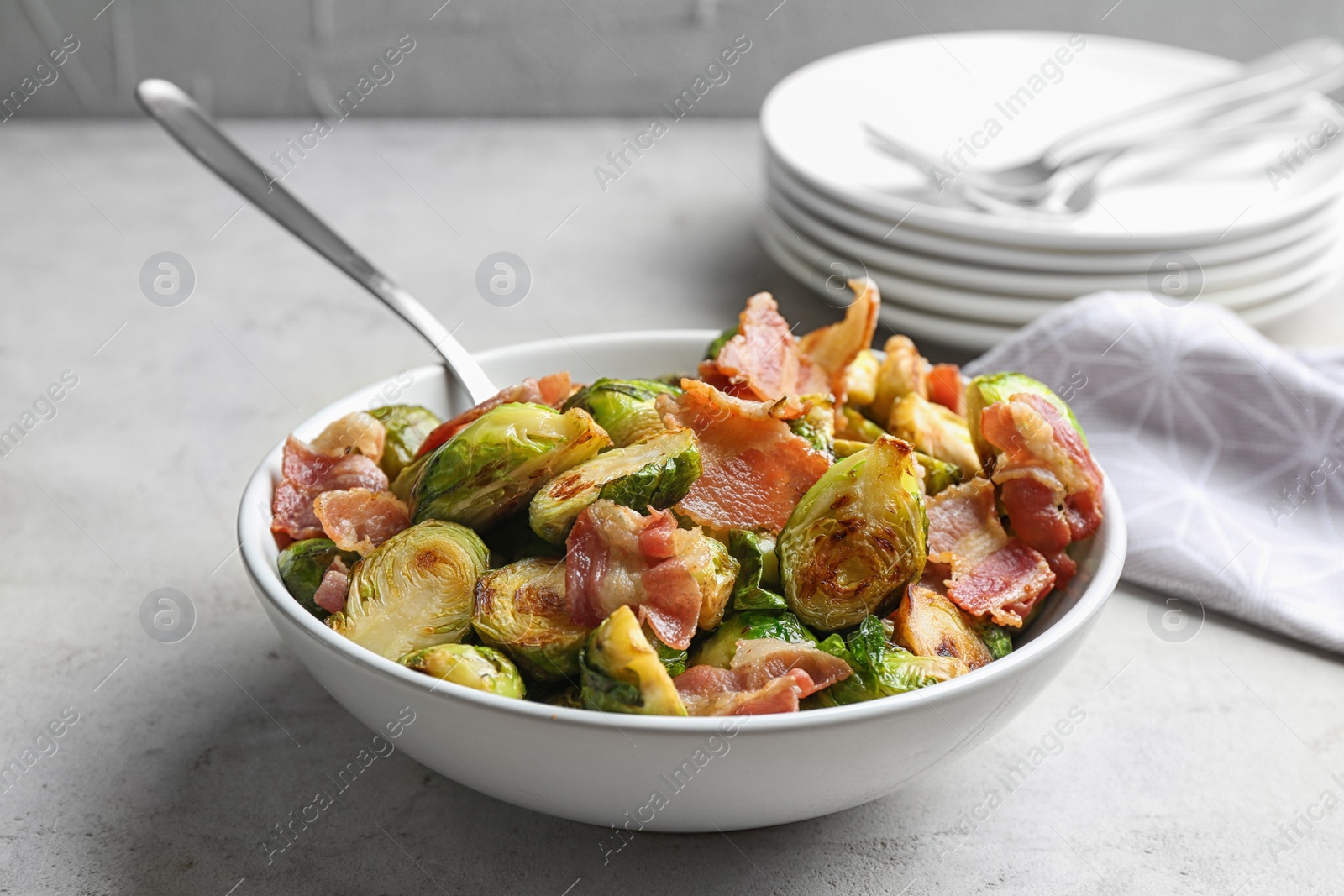 Photo of Delicious roasted Brussels sprouts with bacon served on light grey table