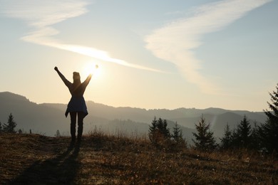 Photo of Woman enjoying sunrise in mountains, back view. Space for text