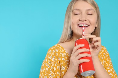 Photo of Beautiful happy woman drinking from red beverage can on light blue background. Space for text