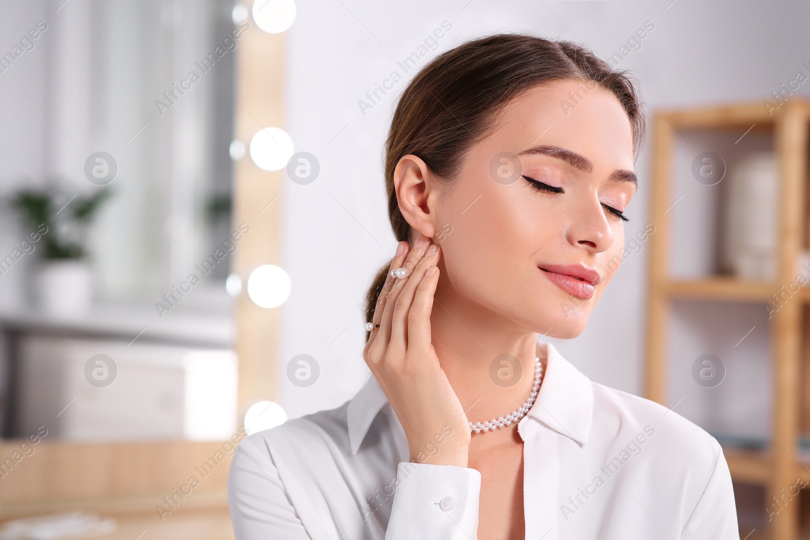 Photo of Young woman wearing elegant pearl jewelry indoors, space for text