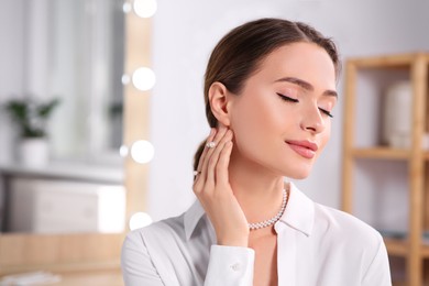 Photo of Young woman wearing elegant pearl jewelry indoors, space for text