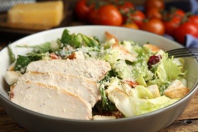 Photo of Delicious Caesar salad in bowl on wooden table, closeup