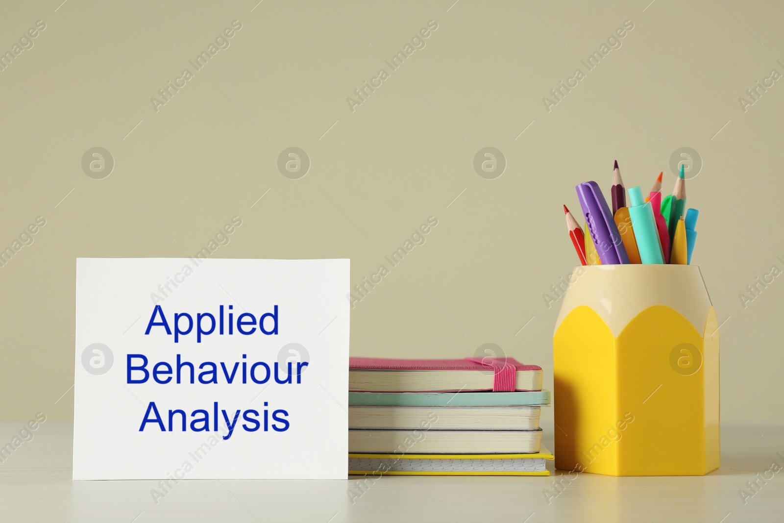 Photo of Set of stationery and card with text Applied Behavior Analysis on wooden table against beige background