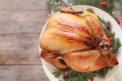 Platter of cooked turkey with garnish and Christmas decoration on wooden background, top view. Space for text