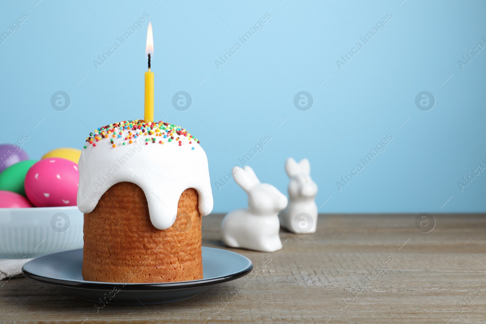 Photo of Easter cake with burning candle on wooden table. space for text