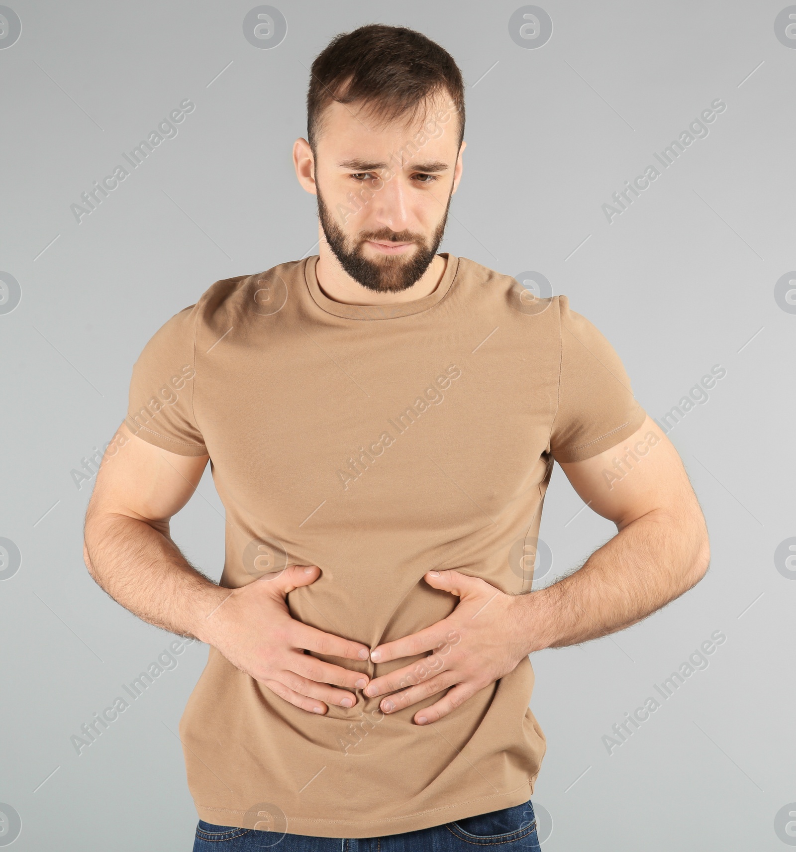 Photo of Young man suffering from abdominal pain on light background