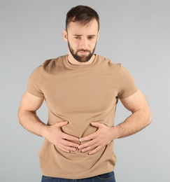 Young man suffering from abdominal pain on light background