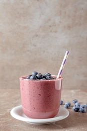 Glass with blueberry smoothie on grey table