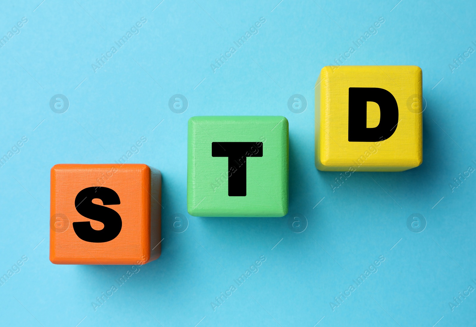 Photo of Abbreviation STD made with cubes on light blue background, flat lay