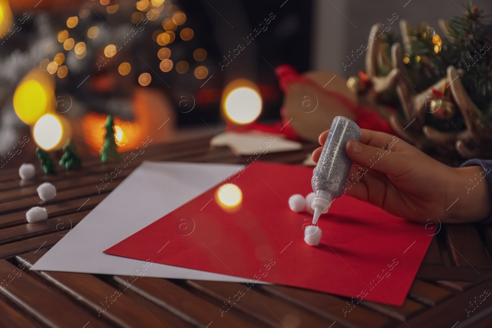 Photo of Little child making Christmas card at wooden table, closeup