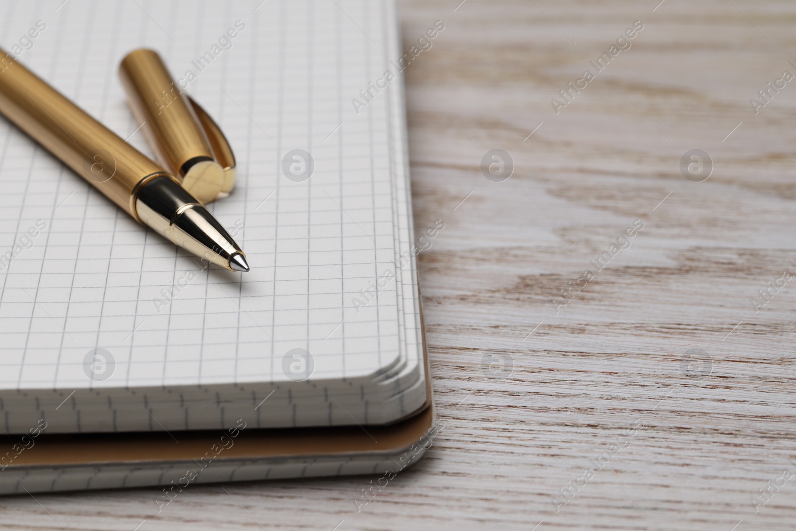 Photo of Ballpoint pen and notebook on wooden table, closeup. Space for text