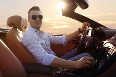 Photo of Businessman driving luxury convertible car outdoors on sunny day