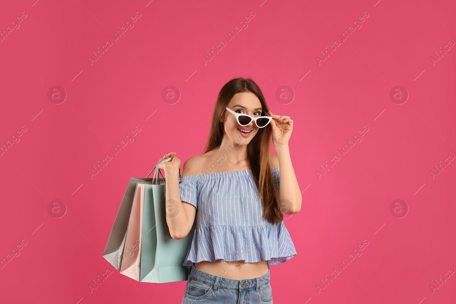 Photo of Beautiful young woman with paper shopping bags on pink background