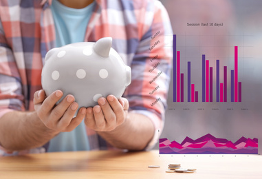 Image of Man with piggy bank and graphs on blurred background, closeup