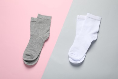 White and grey socks on color background, flat lay