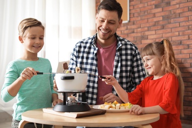 Photo of Children enjoying fondue dinner with father at home