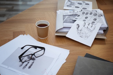 Photo of Detective workplace with documents, glasses and coffee indoors