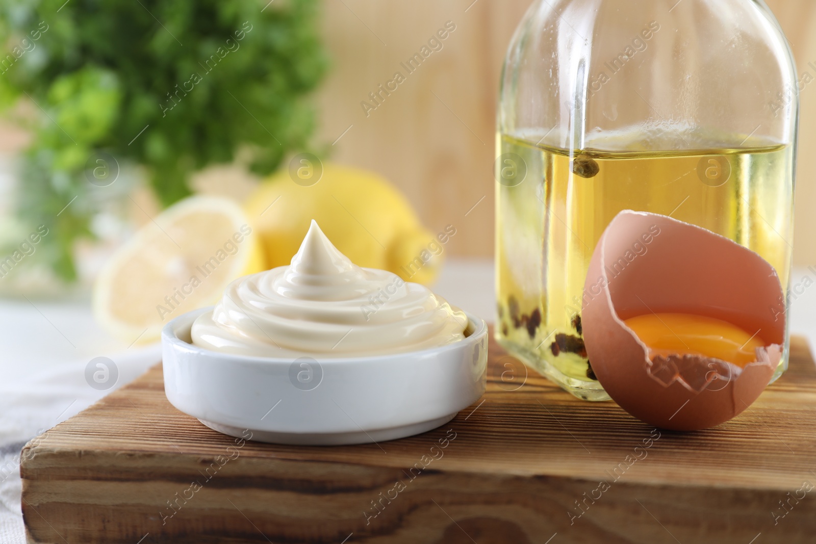 Photo of Fresh mayonnaise sauce in bowl and ingredients on table, closeup