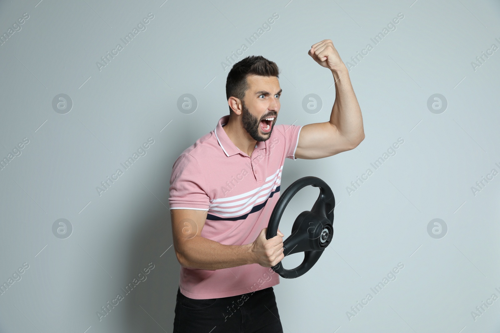 Photo of Emotional man with steering wheel on grey background