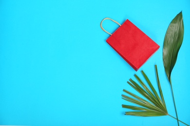 Photo of Stylish flat lay composition with shopping bag and tropical leaves on color background