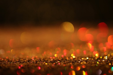 Shiny golden glitter against dark background. Space for text