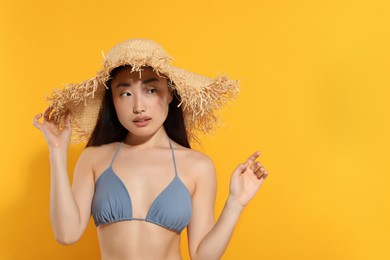 Photo of Beautiful young woman in straw hat on orange background, space for text