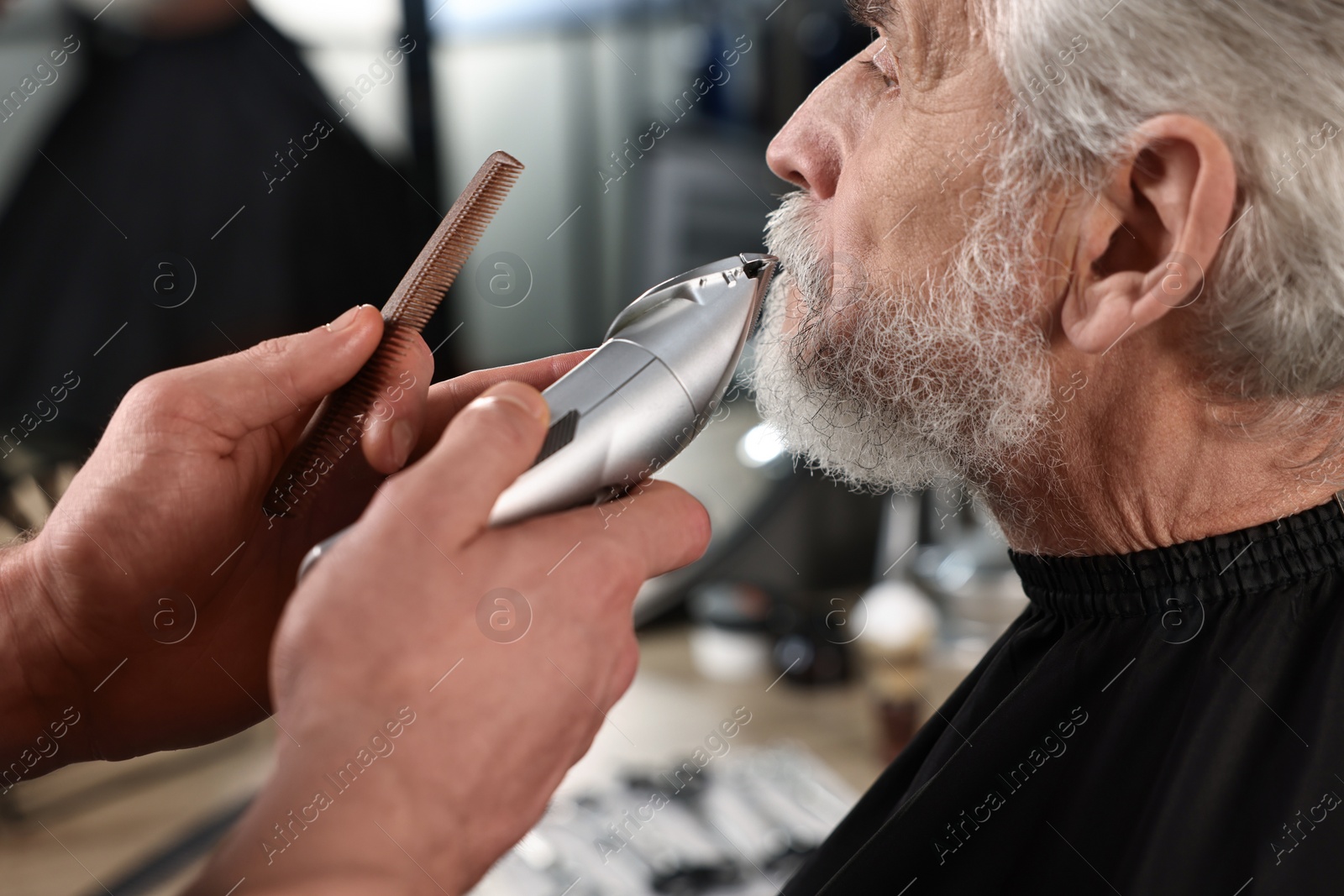 Photo of Professional barber trimming client's mustache in barbershop, closeup