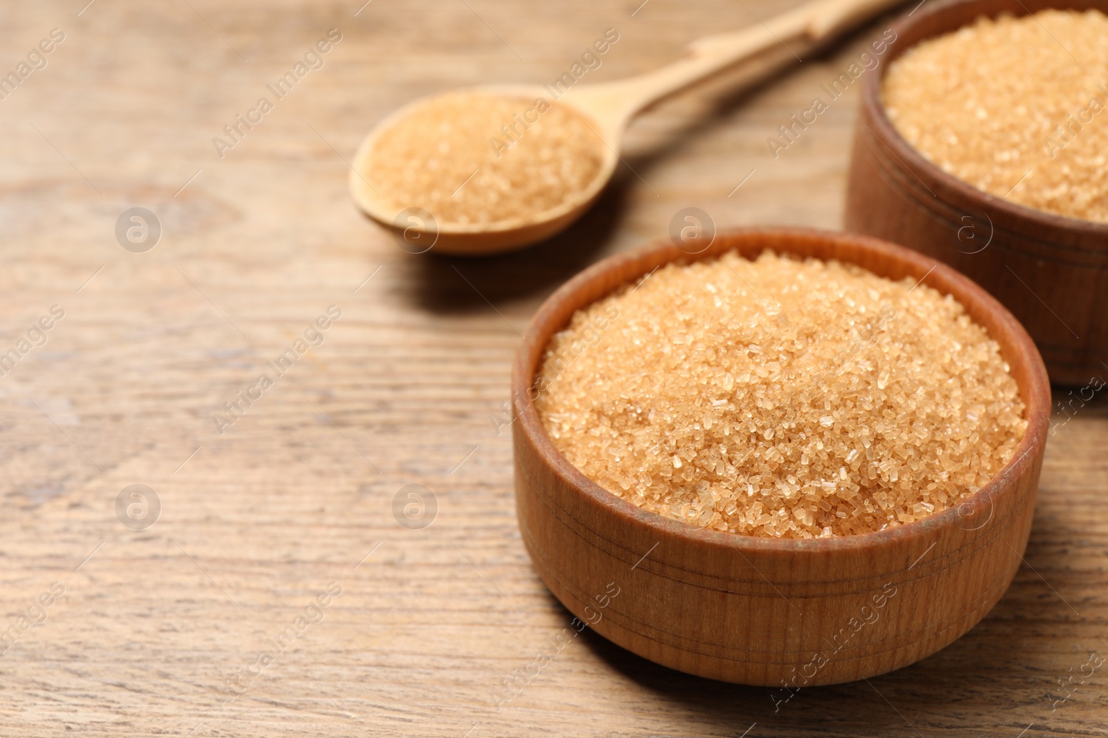 Photo of Different dishes with brown sugar on wooden table, closeup. Space for text