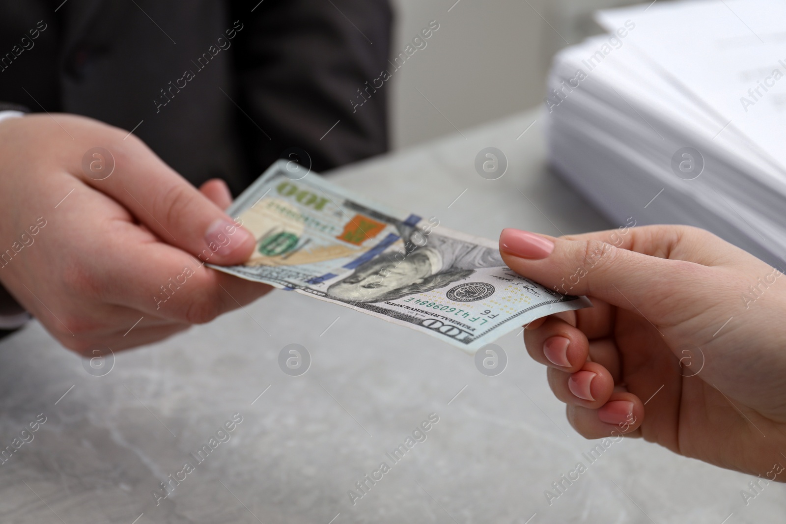 Photo of Woman giving money to man at light grey table, closeup. Currency exchange