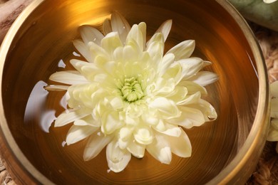 Photo of Tibetan singing bowl with water and beautiful chrysanthemum flower, closeup