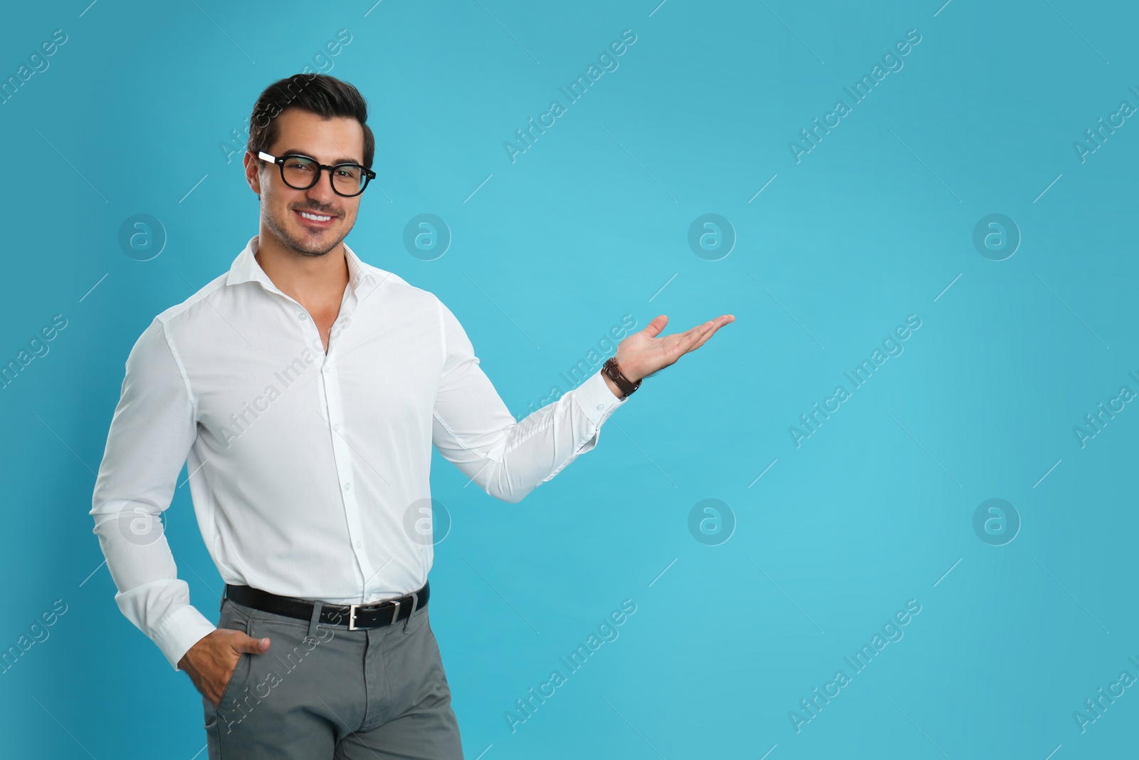 Photo of Young male teacher with glasses on light blue background. Space for text