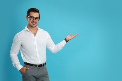 Photo of Young male teacher with glasses on light blue background. Space for text