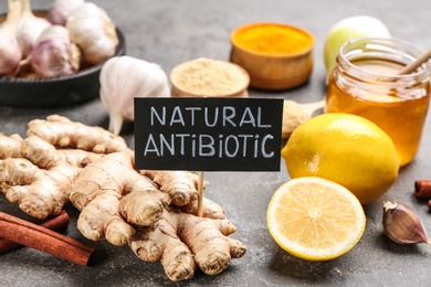 Photo of Different fresh products and card with phrase Natural Antibiotic on grey table